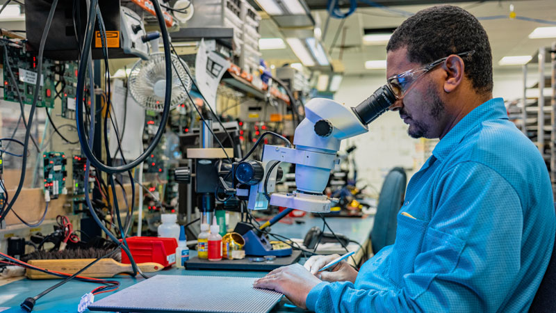 Lab Services worker using microscope on LEDs